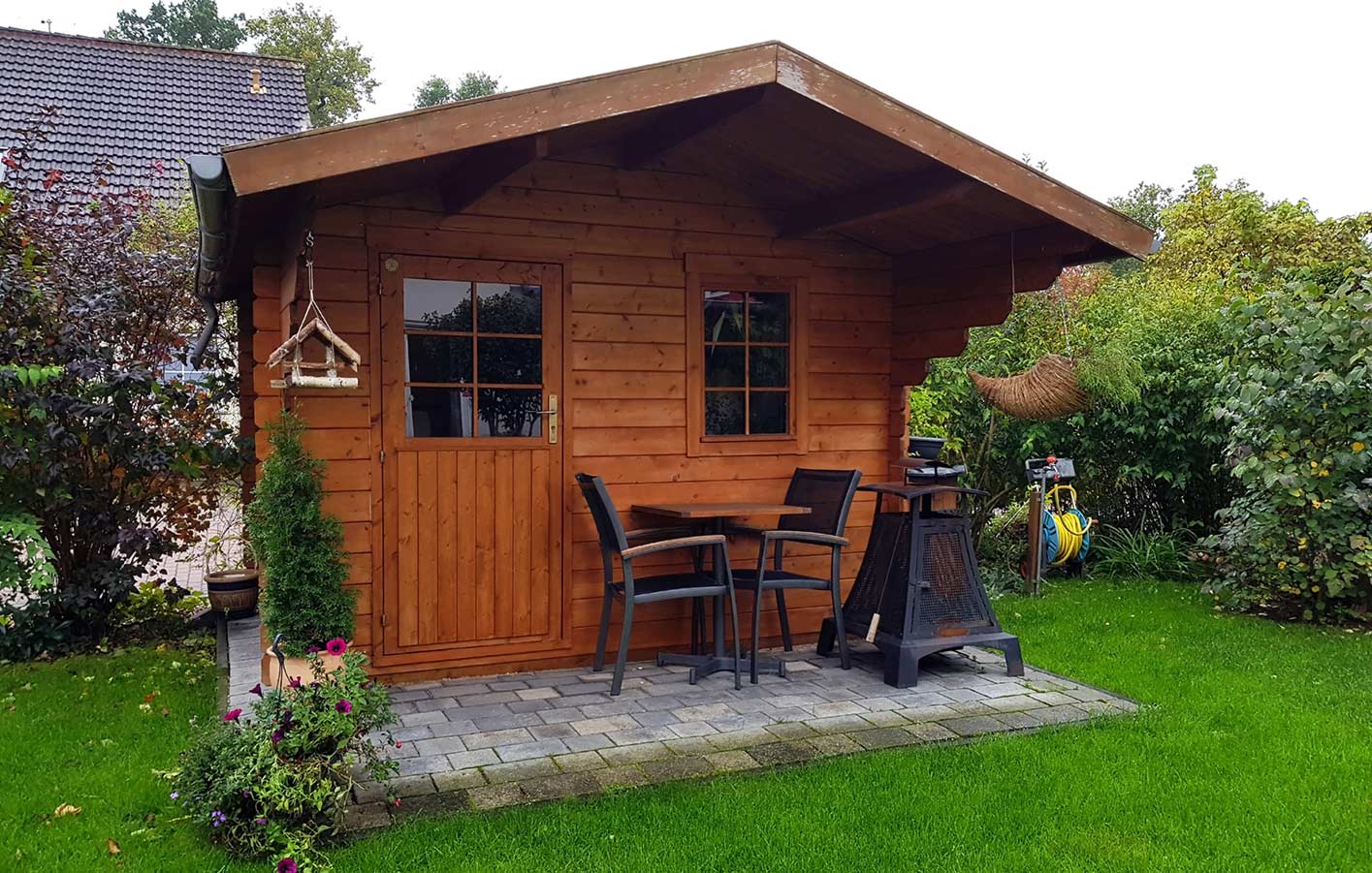 Gartenhaus mit stilvollen Gartenmöbeln Ein Holz-Gartenhaus mit Gartenmöbeln davor, ideal für stilvolle Gartenbereiche.
